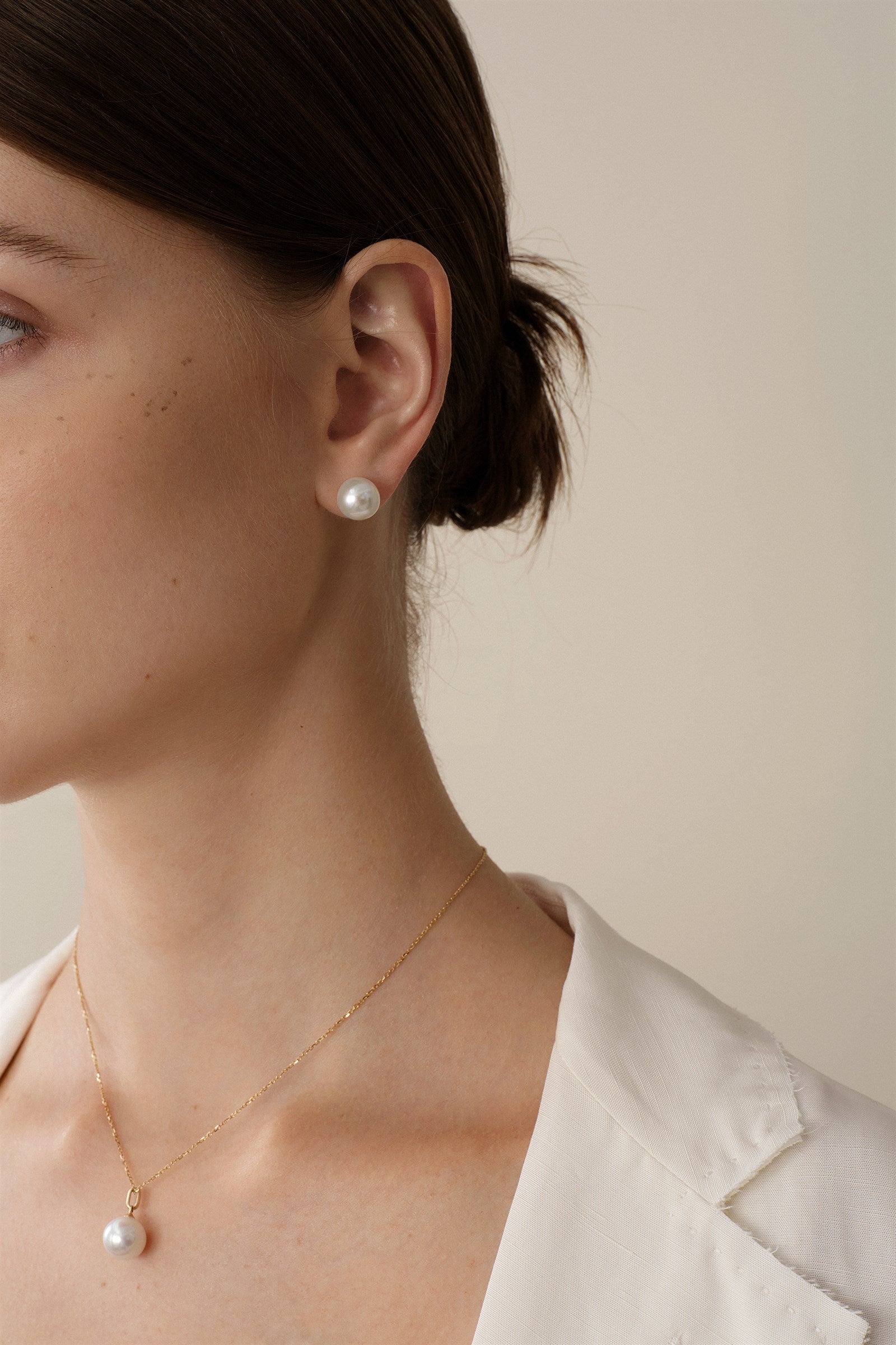 Woman wearing pearl stud earrings with a light blazer for a workday outfit.