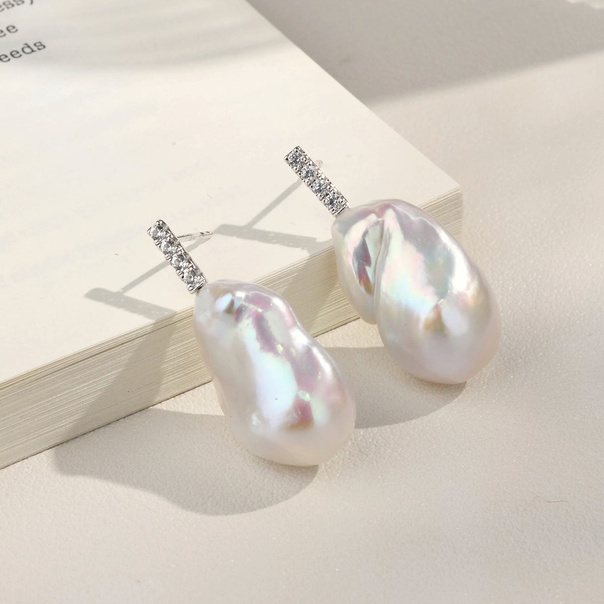 Detail view of baroque freshwater pearl cubic zirconia bar stud earrings in white gold color