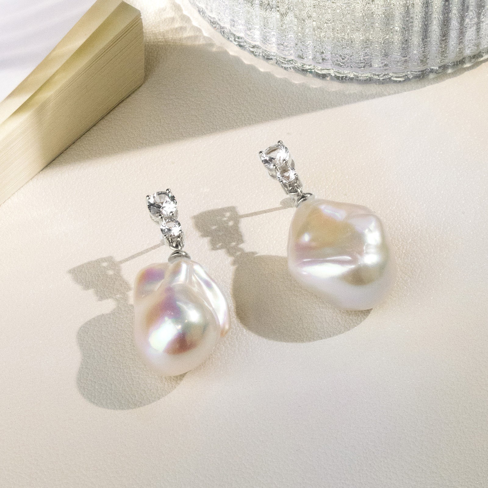 Detail view of baroque freshwater pearl double cubic zirconia stud earrings in white gold color