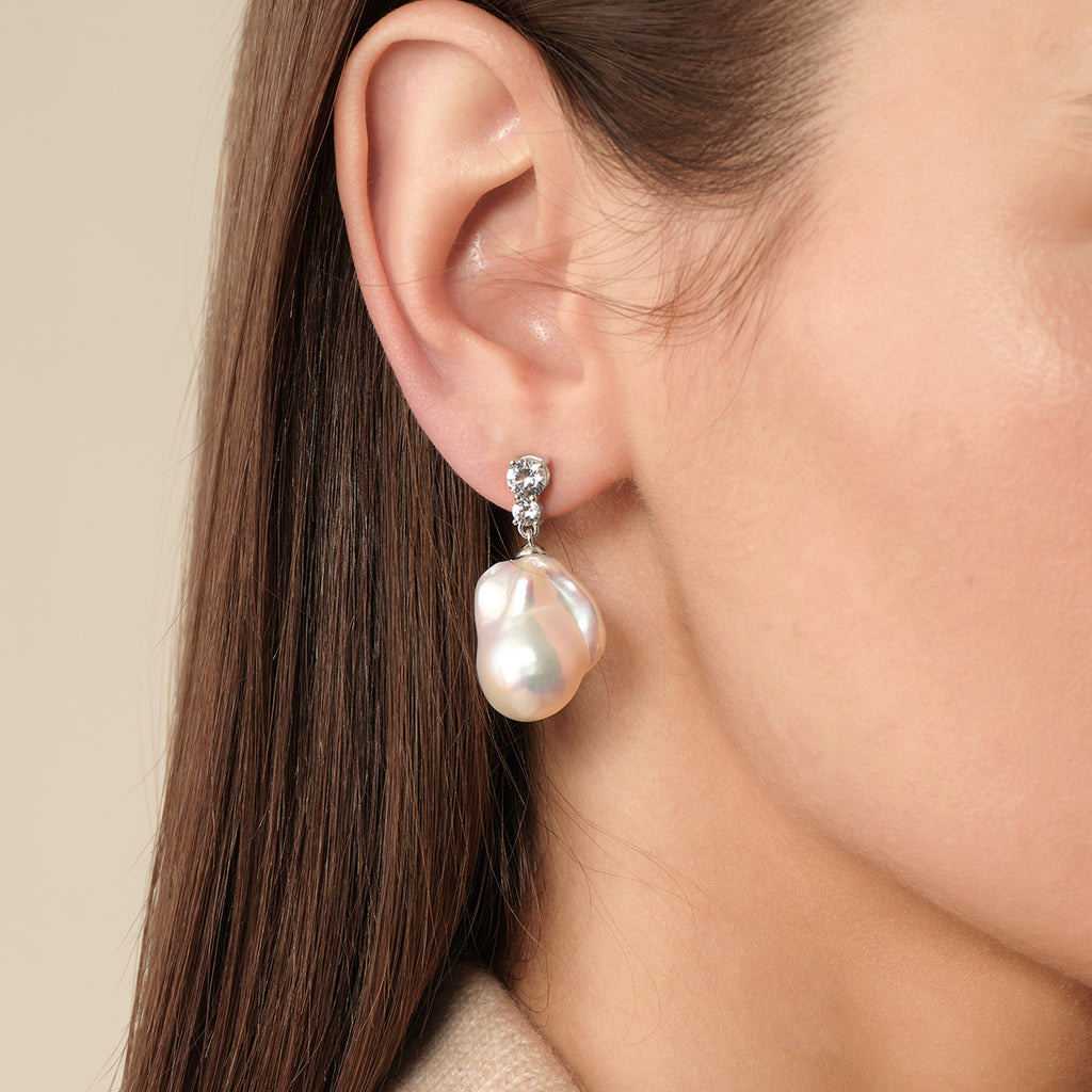 Model wearing baroque freshwater pearl double cubic zirconia stud earrings in white gold color