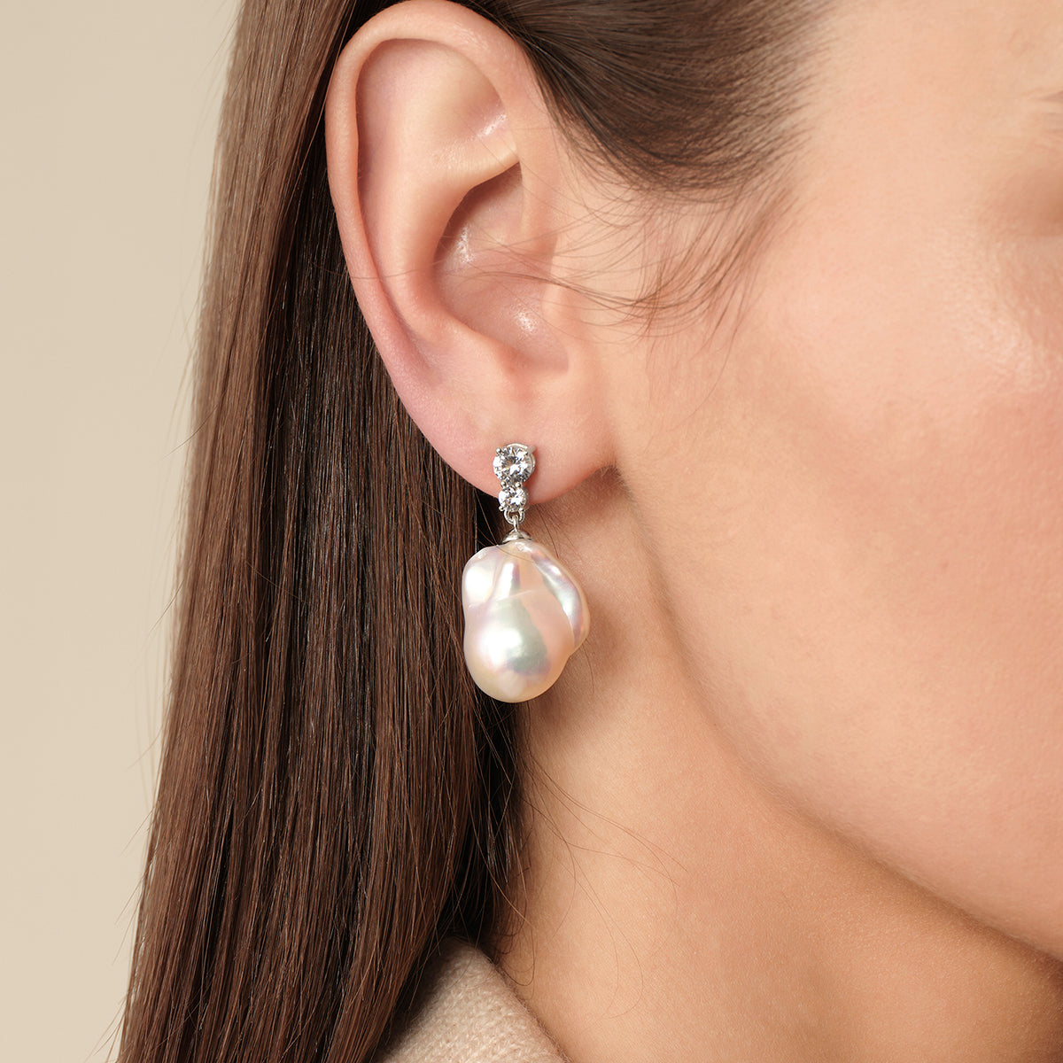 Model wearing baroque freshwater pearl double cubic zirconia stud earrings in white gold color