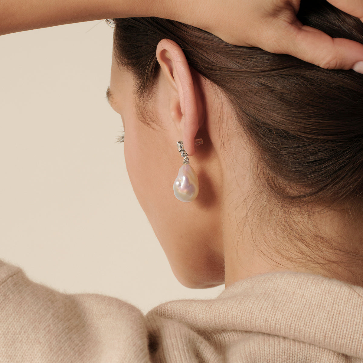 Model wearing baroque freshwater pearl double cubic zirconia stud earrings in white gold color, lifestyle view