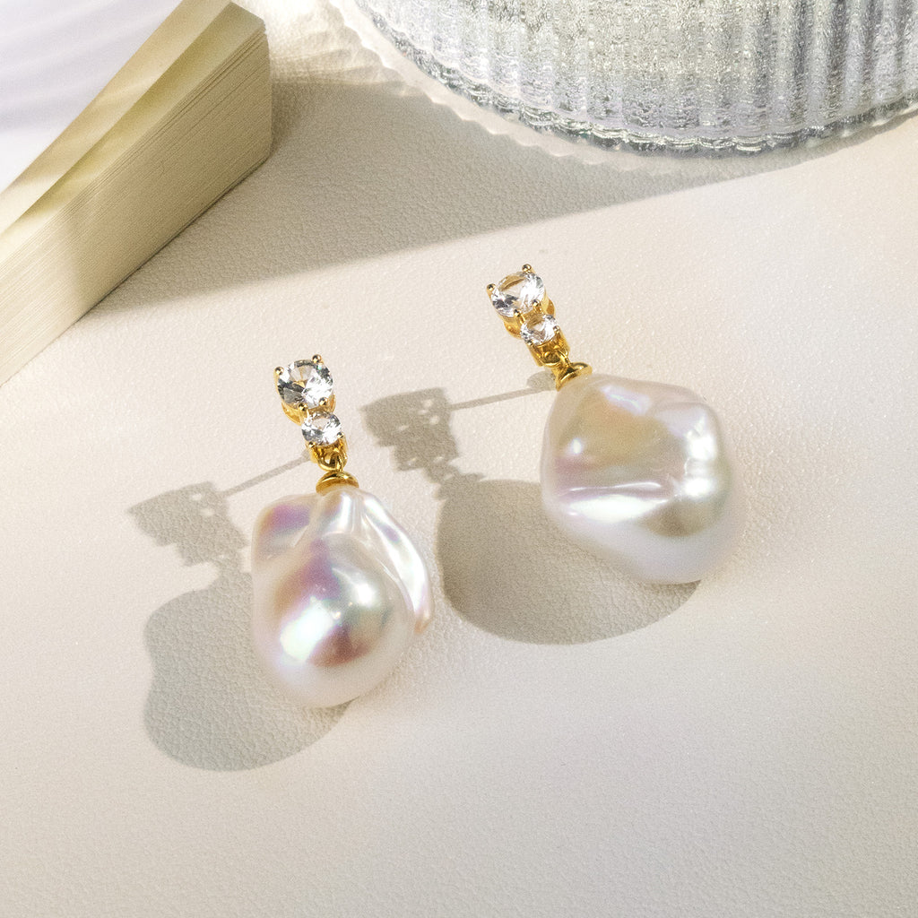 Model wearing baroque freshwater pearl double cubic zirconia stud earrings in yellow gold color