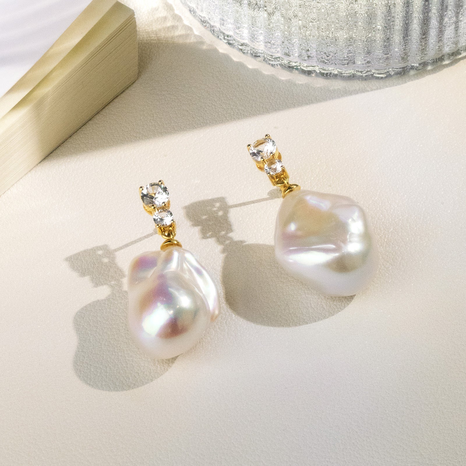 Model wearing baroque freshwater pearl double cubic zirconia stud earrings in yellow gold color