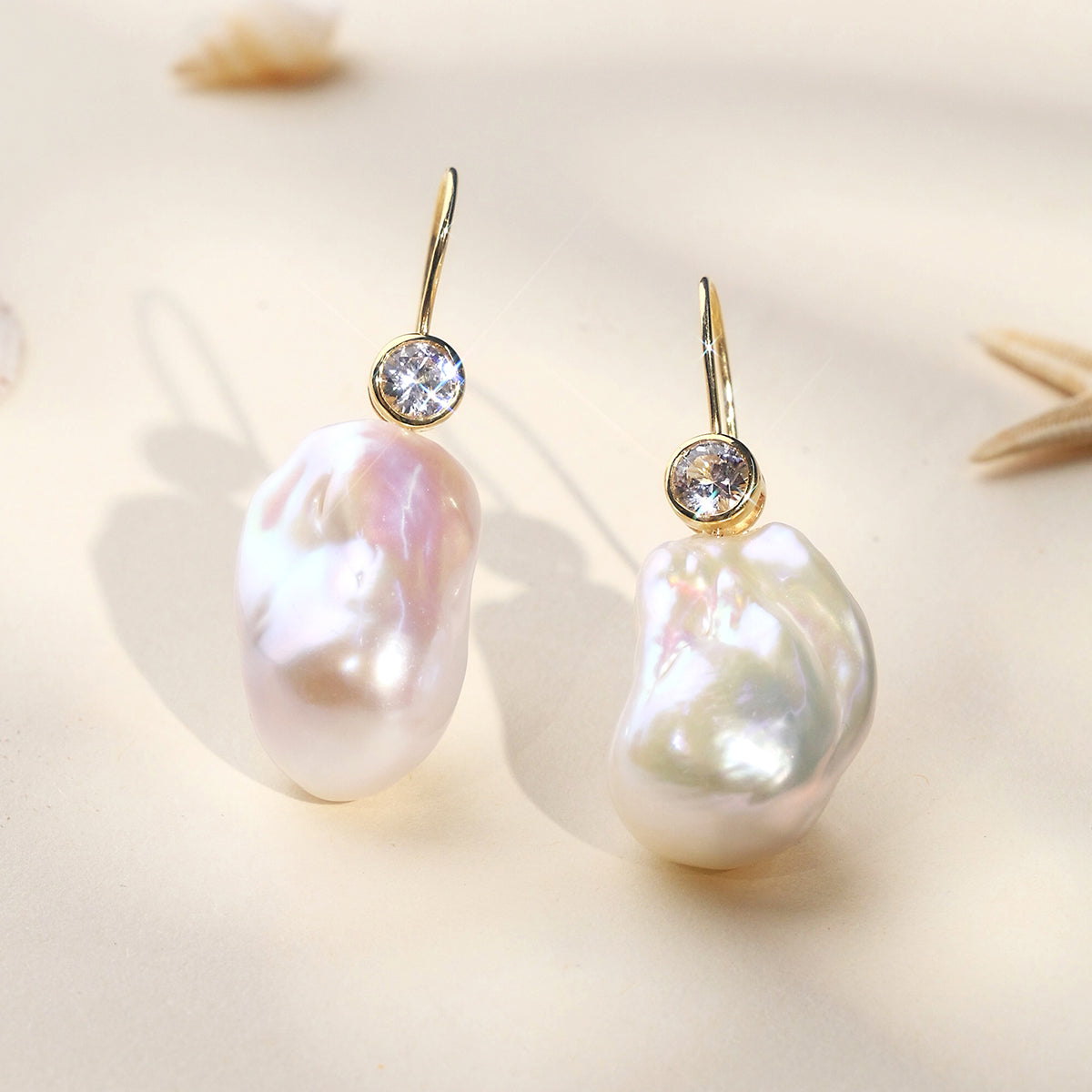 Detail view of baroque freshwater pearl and round cubic zirconia hook earrings in yellow gold color