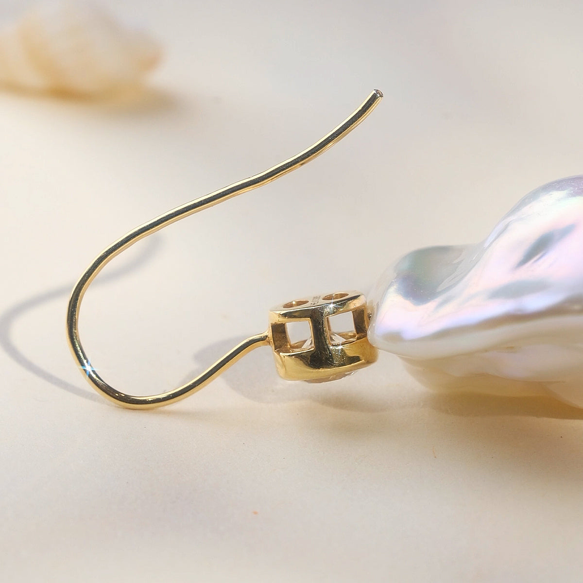 Close-up of baroque freshwater pearl and round cubic zirconia hook earrings in yellow gold color