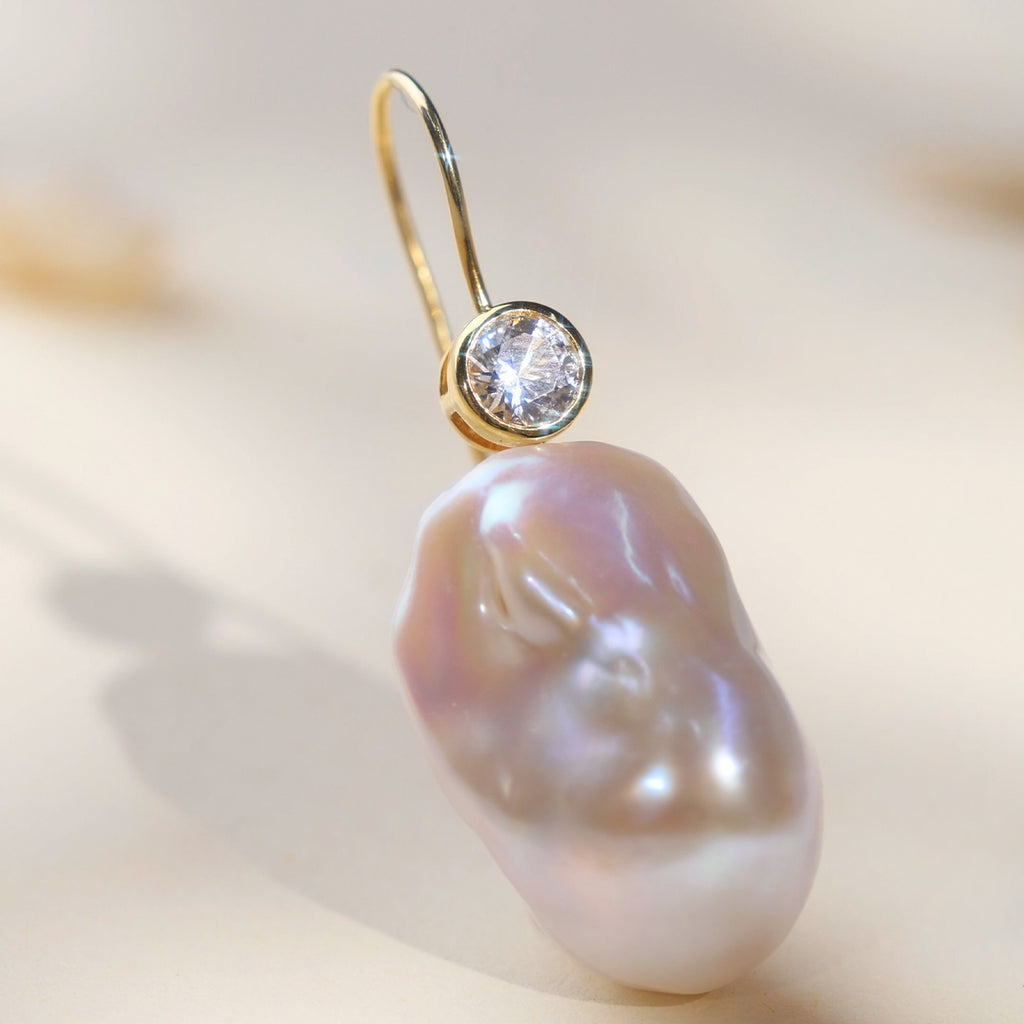 Model wearing baroque freshwater pearl and round cubic zirconia hook earrings in yellow gold color
