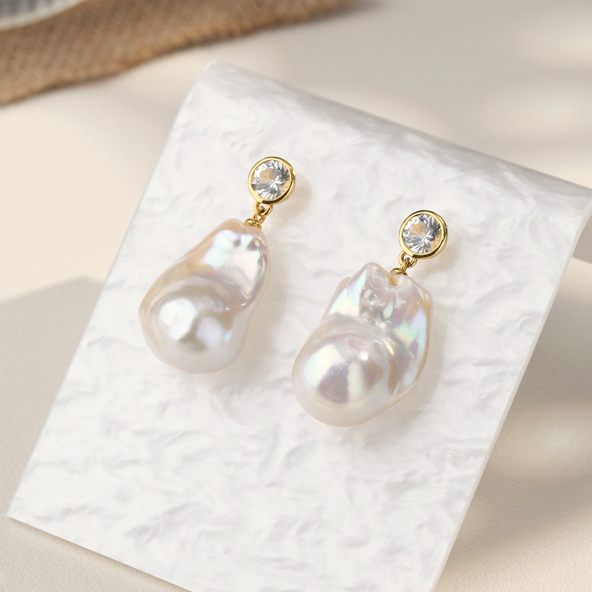Detail view of baroque freshwater pearl round cubic zirconia stud earrings in yellow gold color