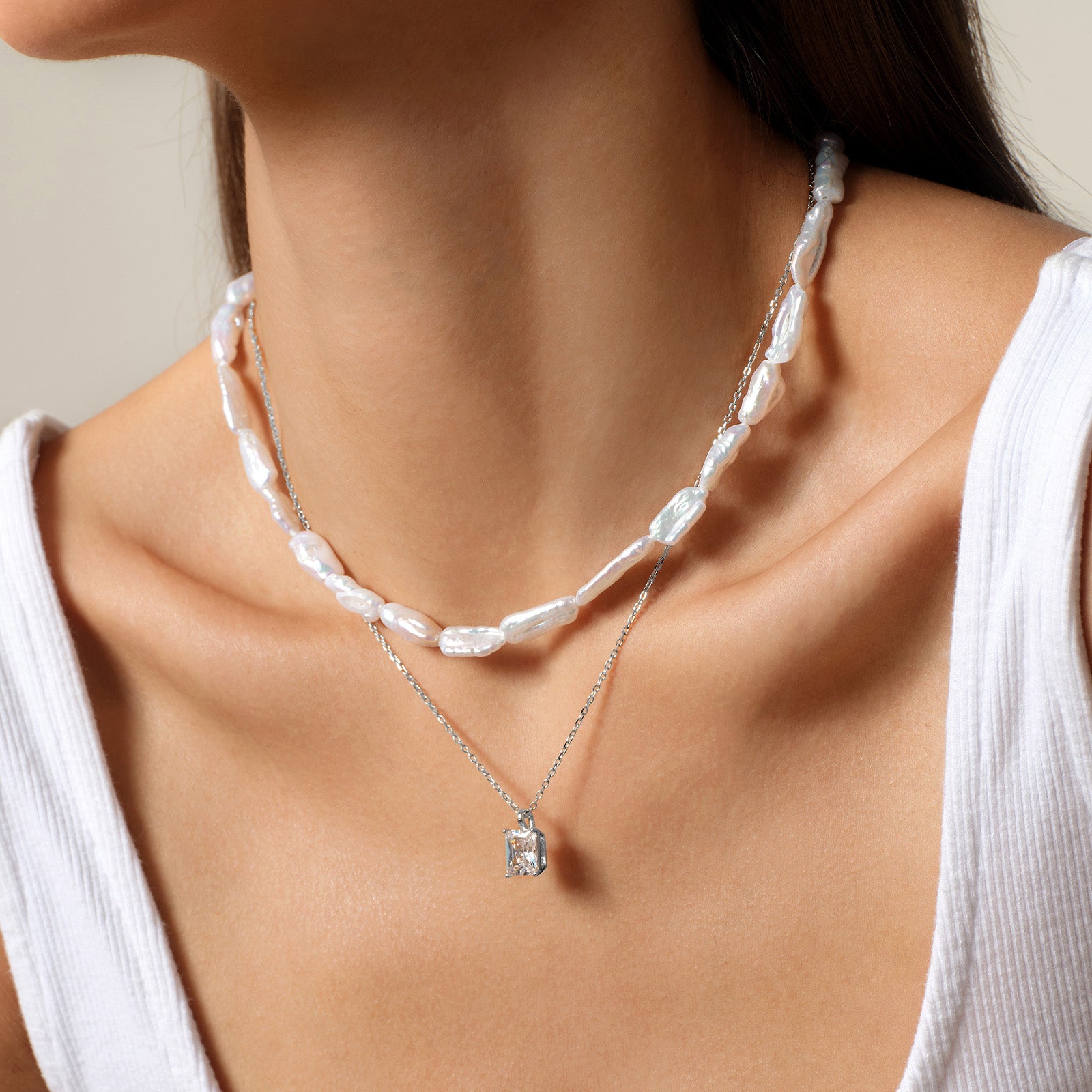 Model wearing emerald-cut cubic zirconia pendant necklace in white gold color, close view