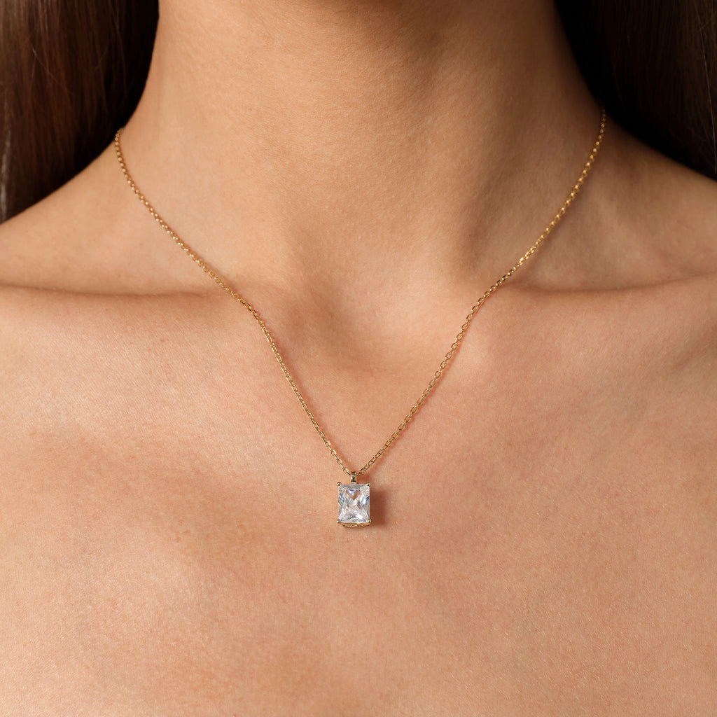 Model wearing emerald-cut cubic zirconia pendant necklace in yellow gold color