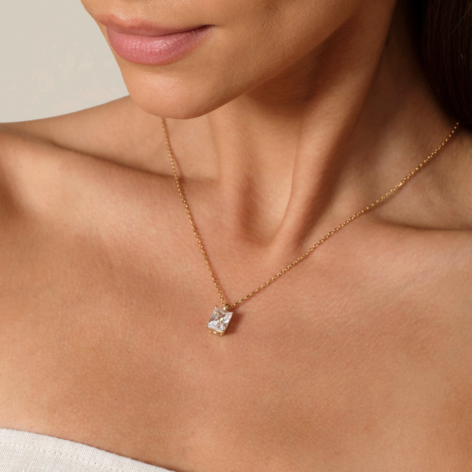 Model wearing emerald-cut cubic zirconia pendant necklace in yellow gold color, close view