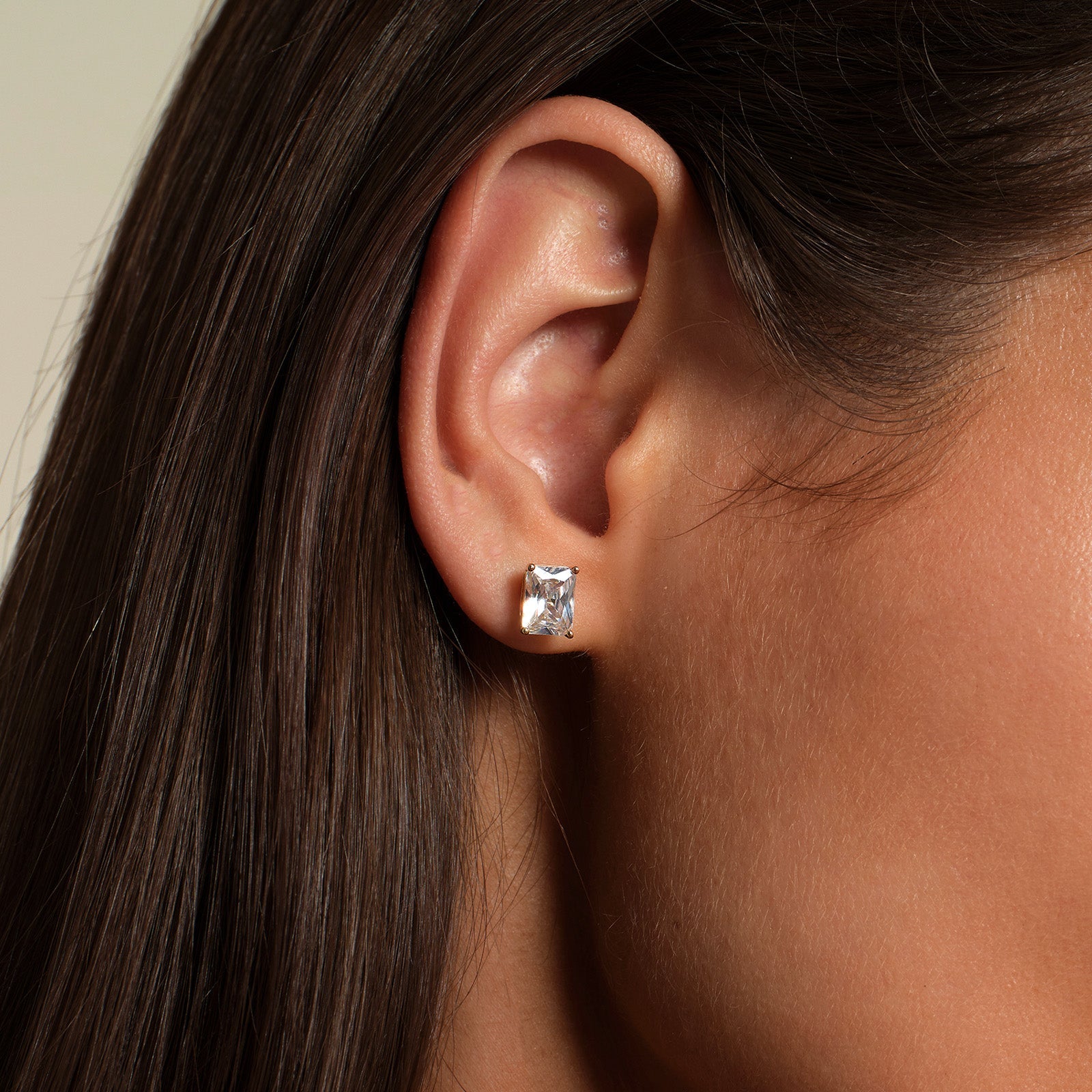 Close-up of model wearing emerald-cut cubic zirconia stud earrings in gold color