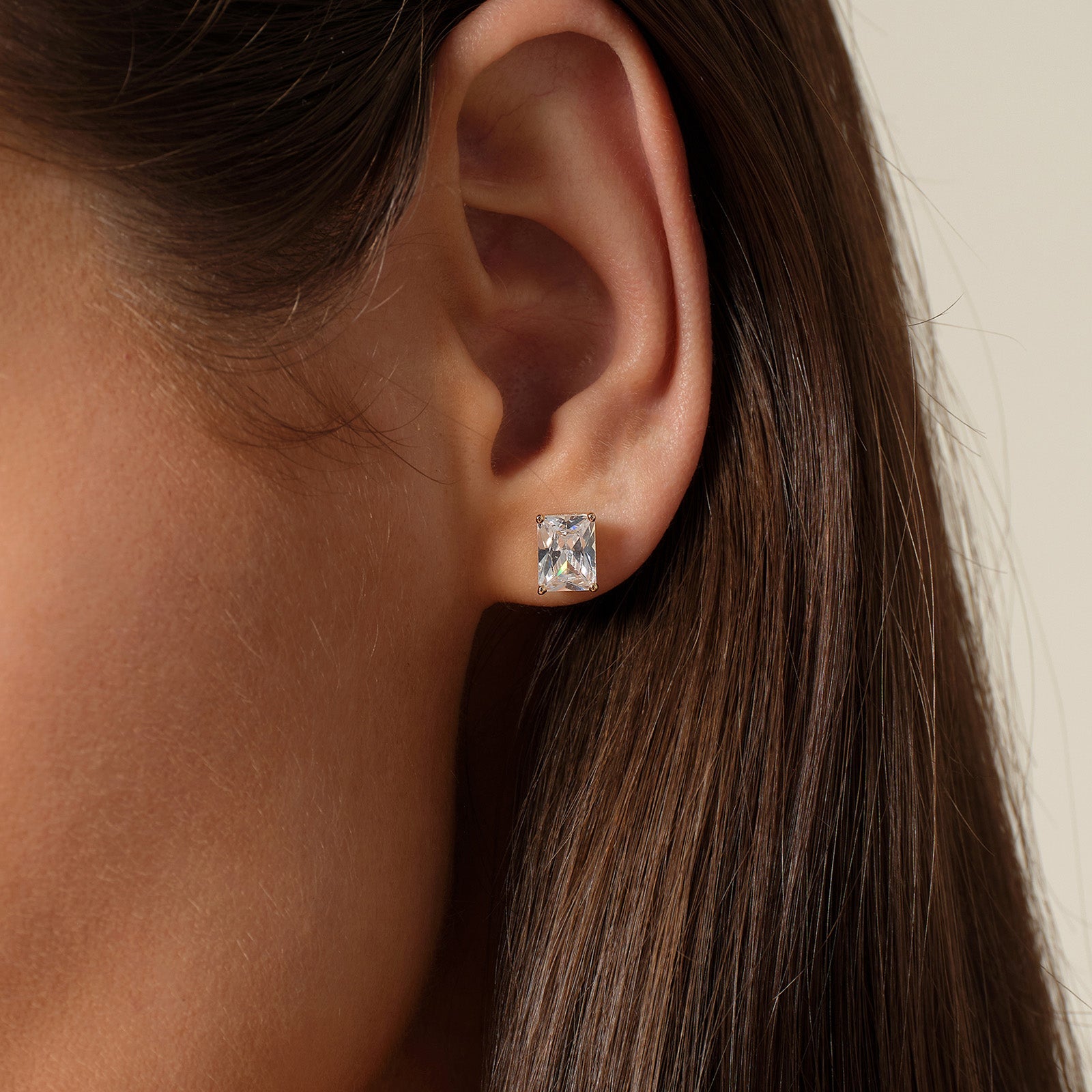 Model wearing emerald-cut cubic zirconia stud earrings in gold color