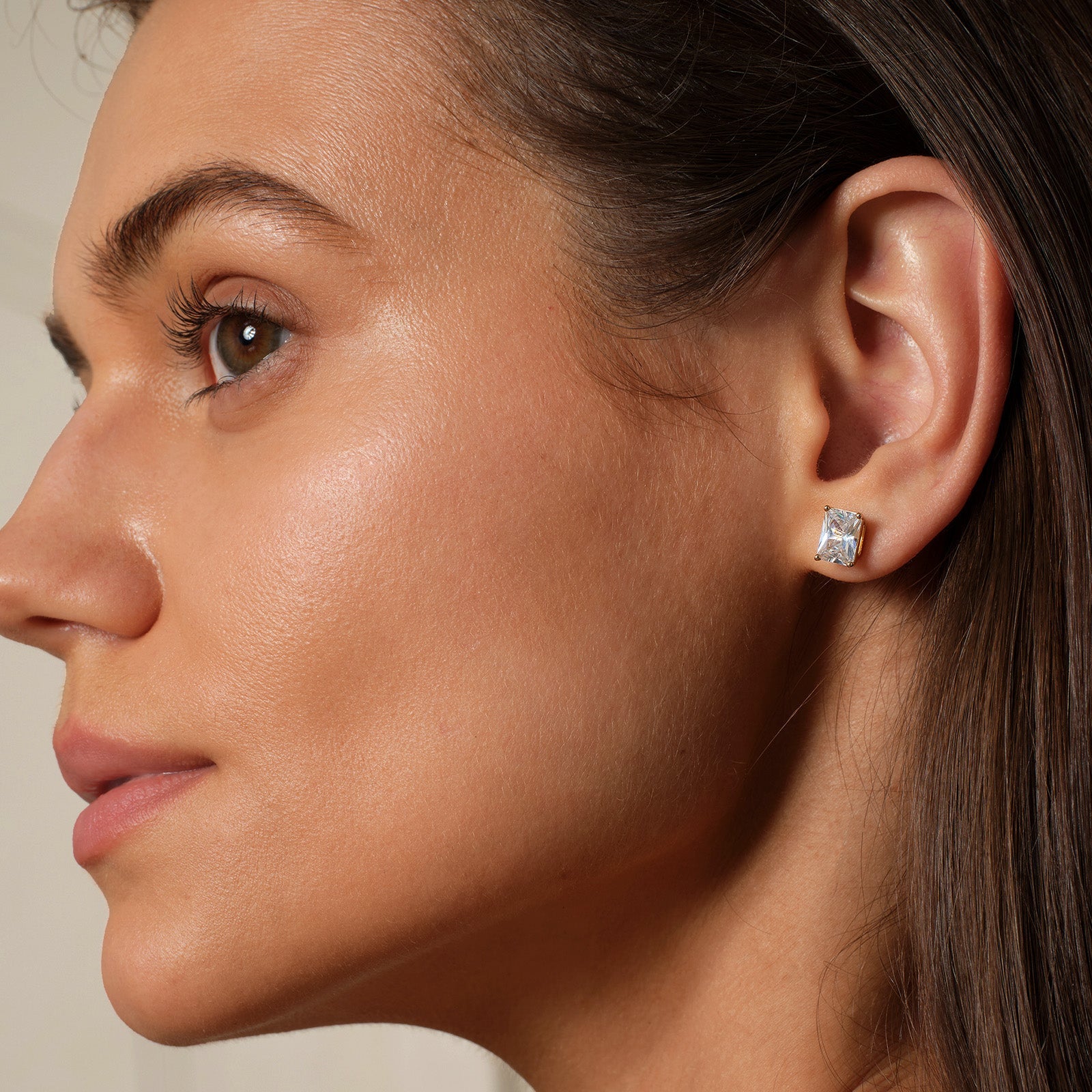 Model wearing emerald-cut cubic zirconia stud earrings in gold color with neutral outfit