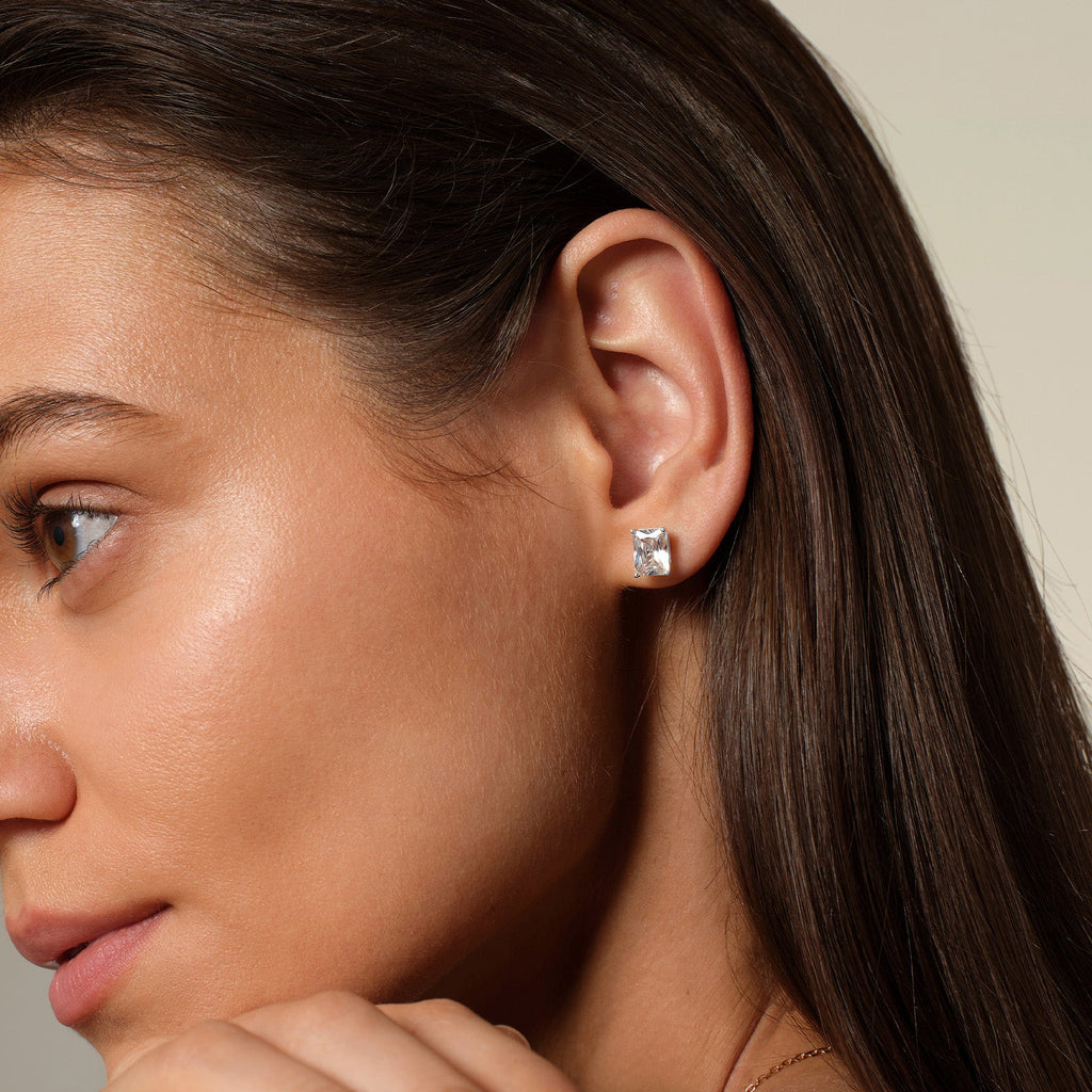Model wearing emerald-cut cubic zirconia stud earrings in silver color with neutral outfit