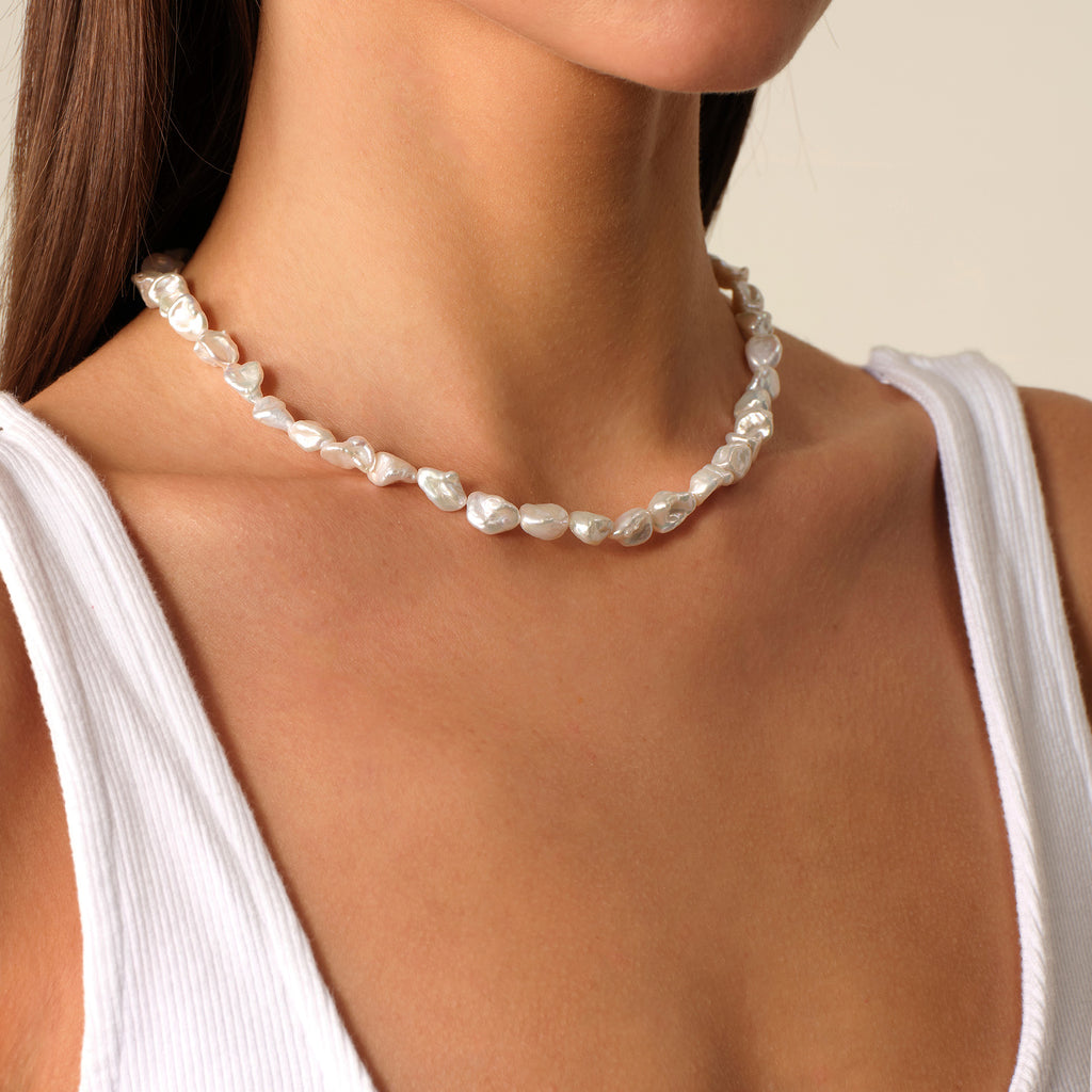 Model wearing a freshwater Keshi pearl strand necklace with a white top