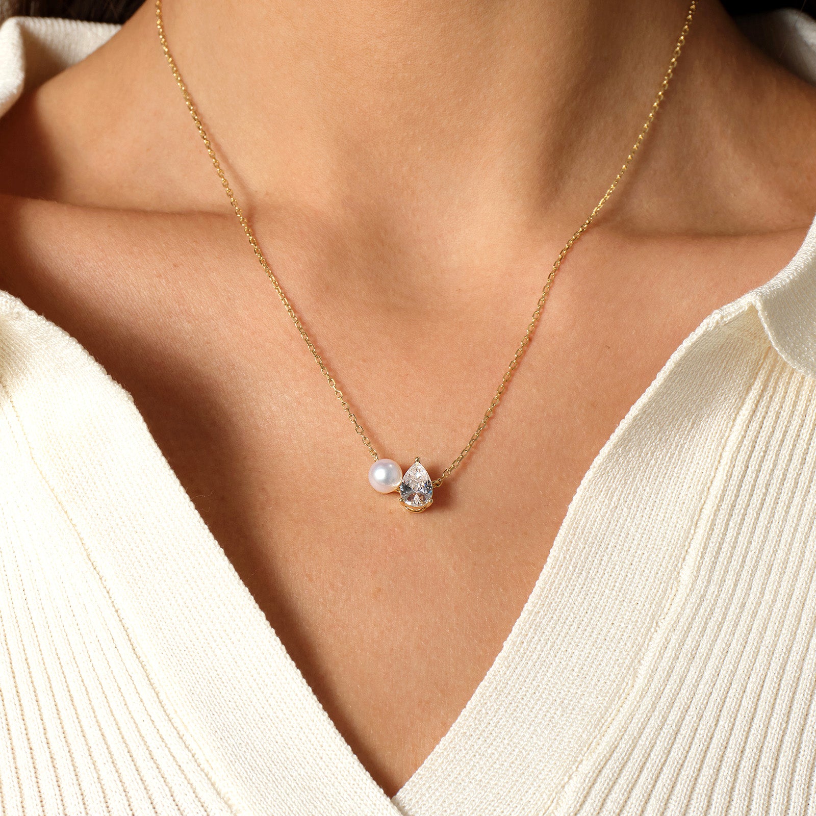 Model wearing freshwater pearl and pear-shaped cubic zirconia pendant necklace in yellow gold color