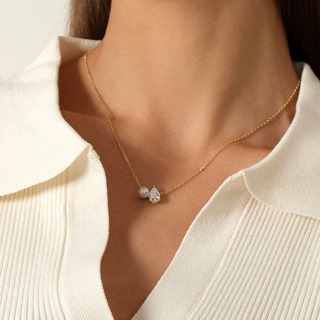 Close-up of model wearing freshwater pearl and pear-shaped cubic zirconia pendant necklace in yellow gold color