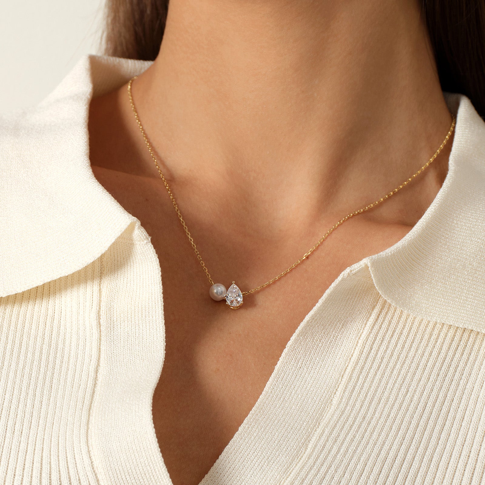 Close-up of model wearing freshwater pearl and pear-shaped cubic zirconia pendant necklace in yellow gold color