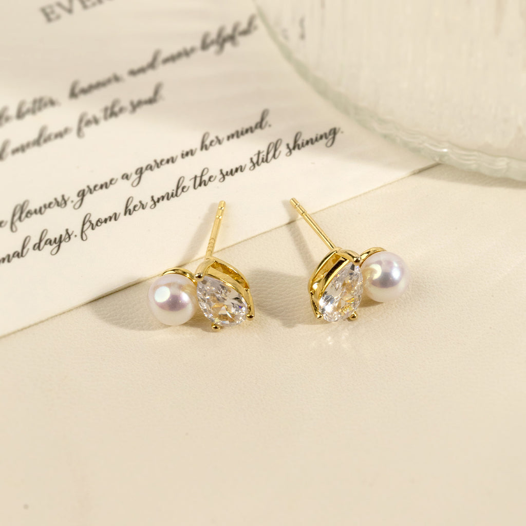 Model wearing freshwater pearl and pear-shaped cubic zirconia stud earrings in yellow gold color