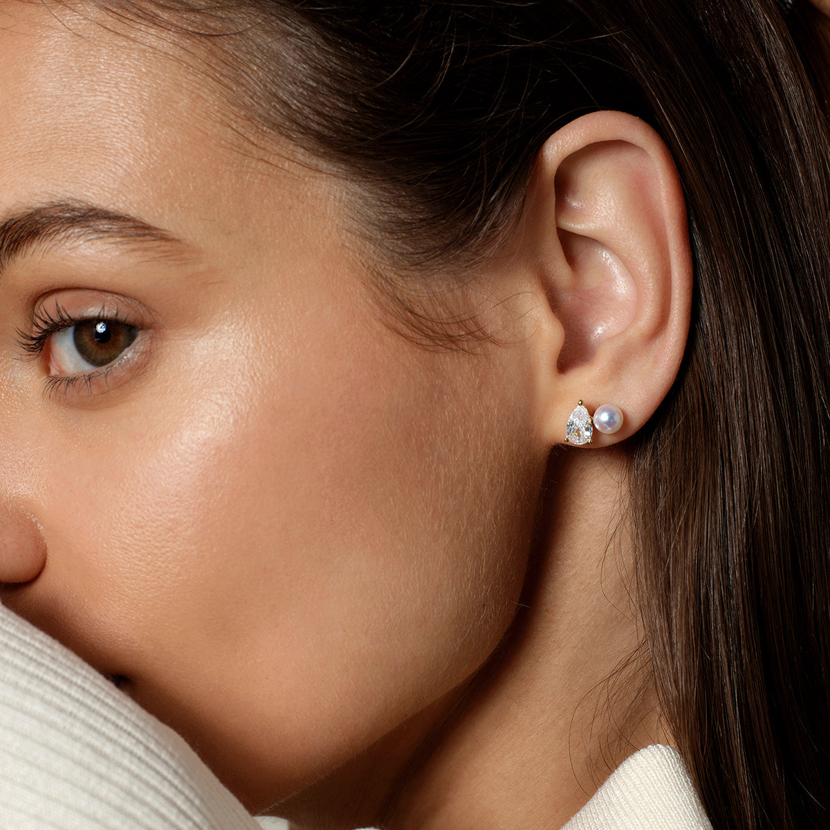 Freshwater pearl and pear-shaped cubic zirconia stud earrings in yellow gold color worn on model