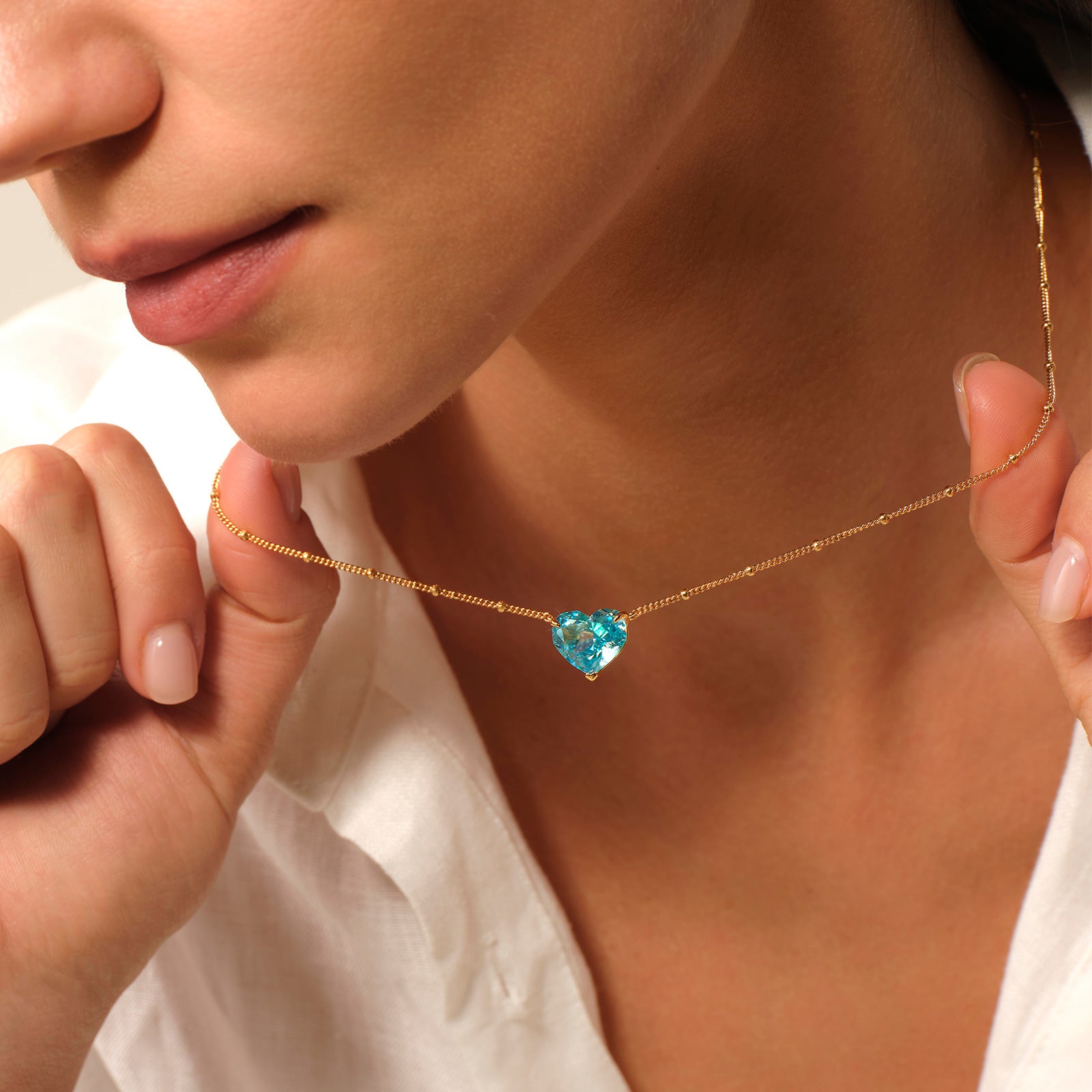 Close-up of a model wearing a blue heart cubic zirconia pendant necklace