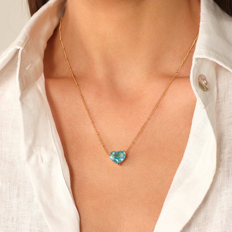 Model wearing a blue heart cubic zirconia pendant necklace with an open white shirt