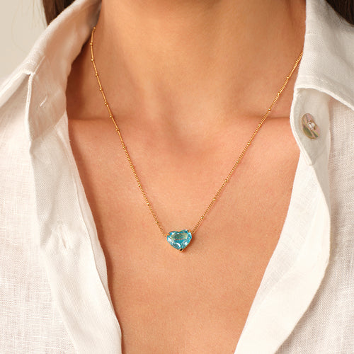Model wearing a blue heart cubic zirconia pendant necklace with an open white shirt