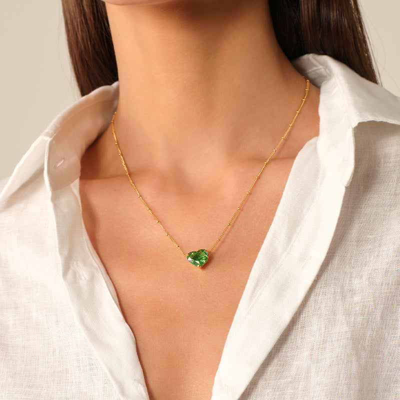 Model wearing a green heart cubic zirconia pendant necklace with an open white shirt