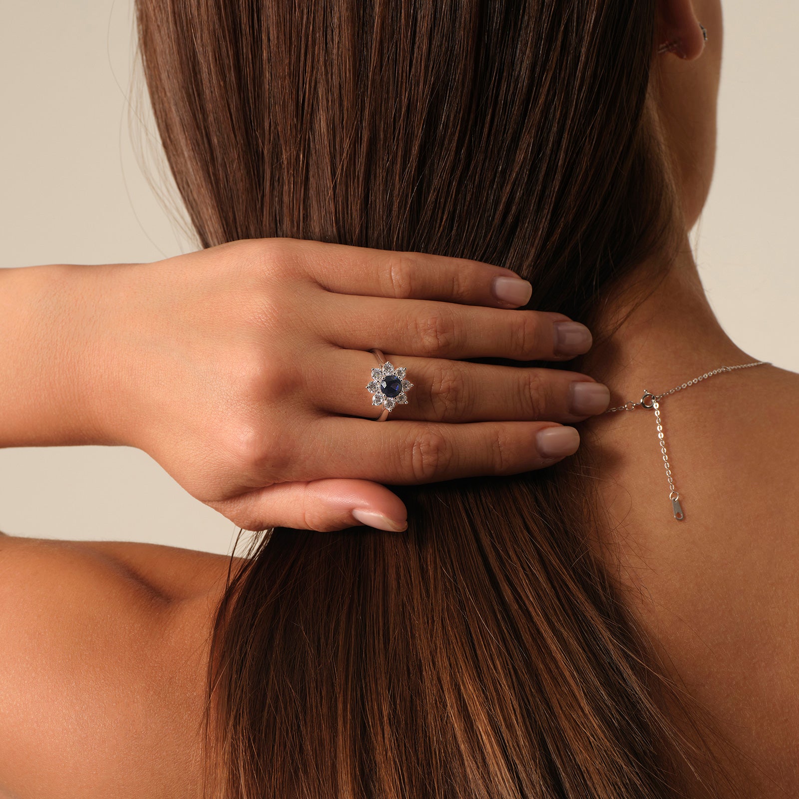 Model wearing a sapphire floral halo ring with the open silver band visible