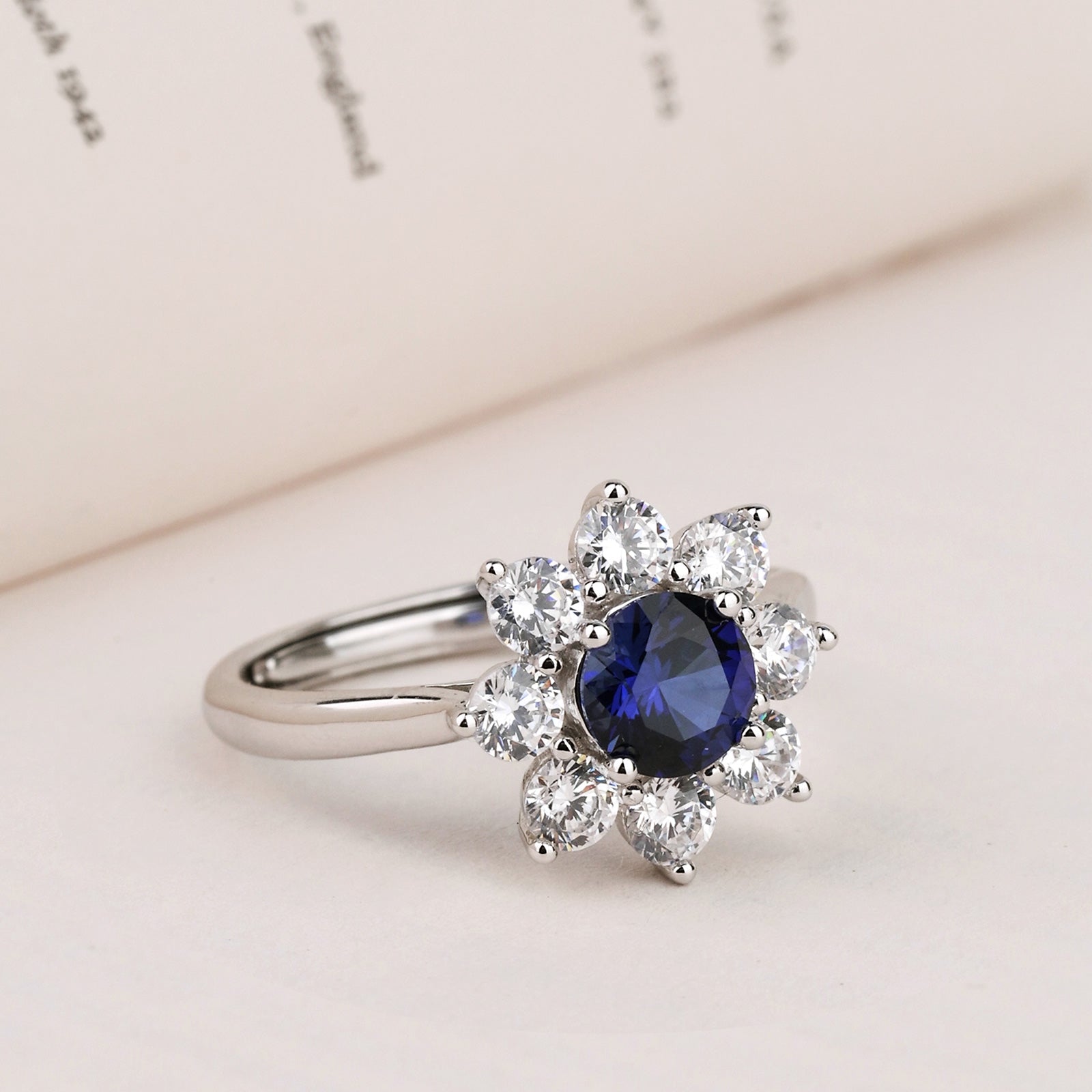 Lab-created sapphire floral halo ring shown on a neutral surface
