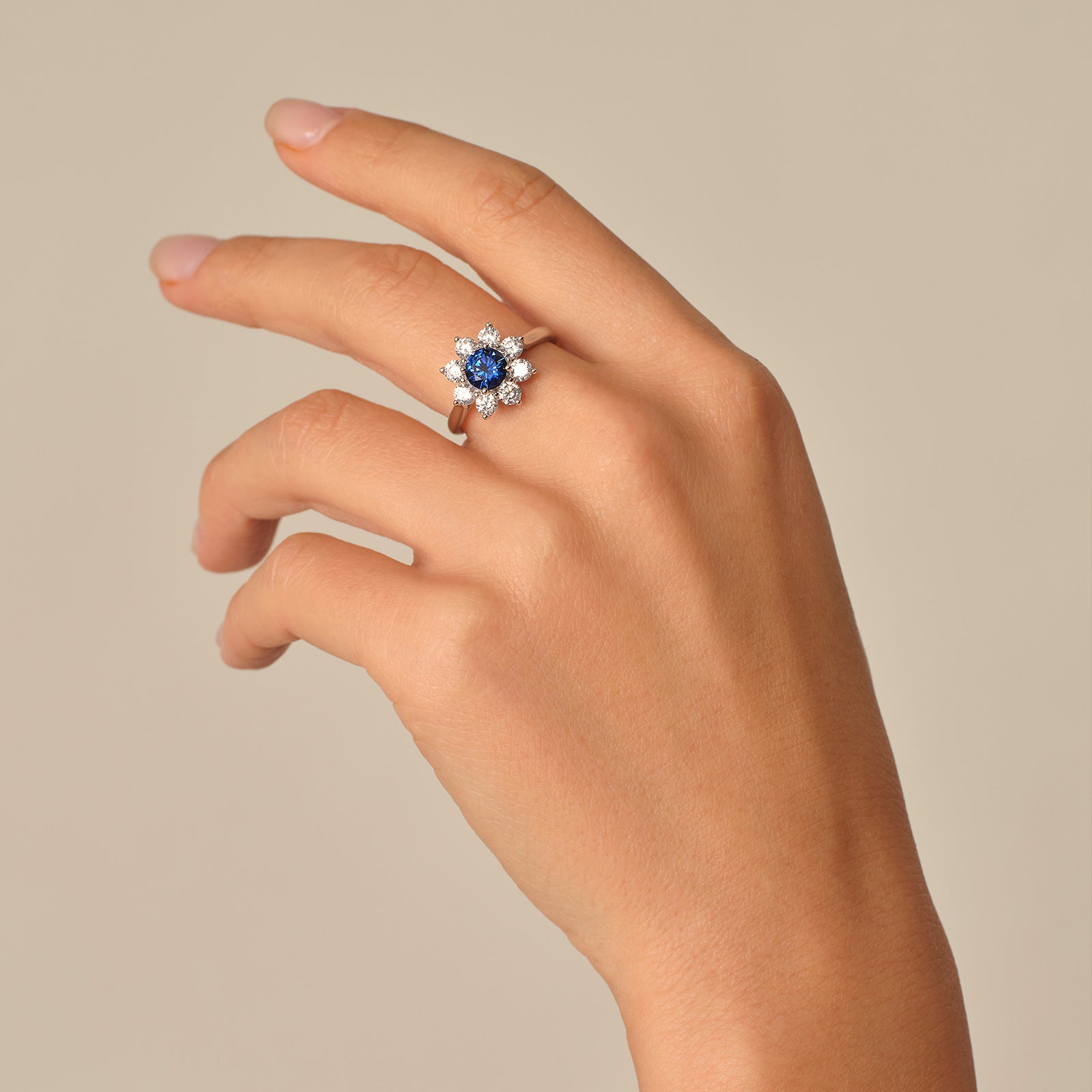 Hand view of a blue sapphire floral halo ring in sterling silver