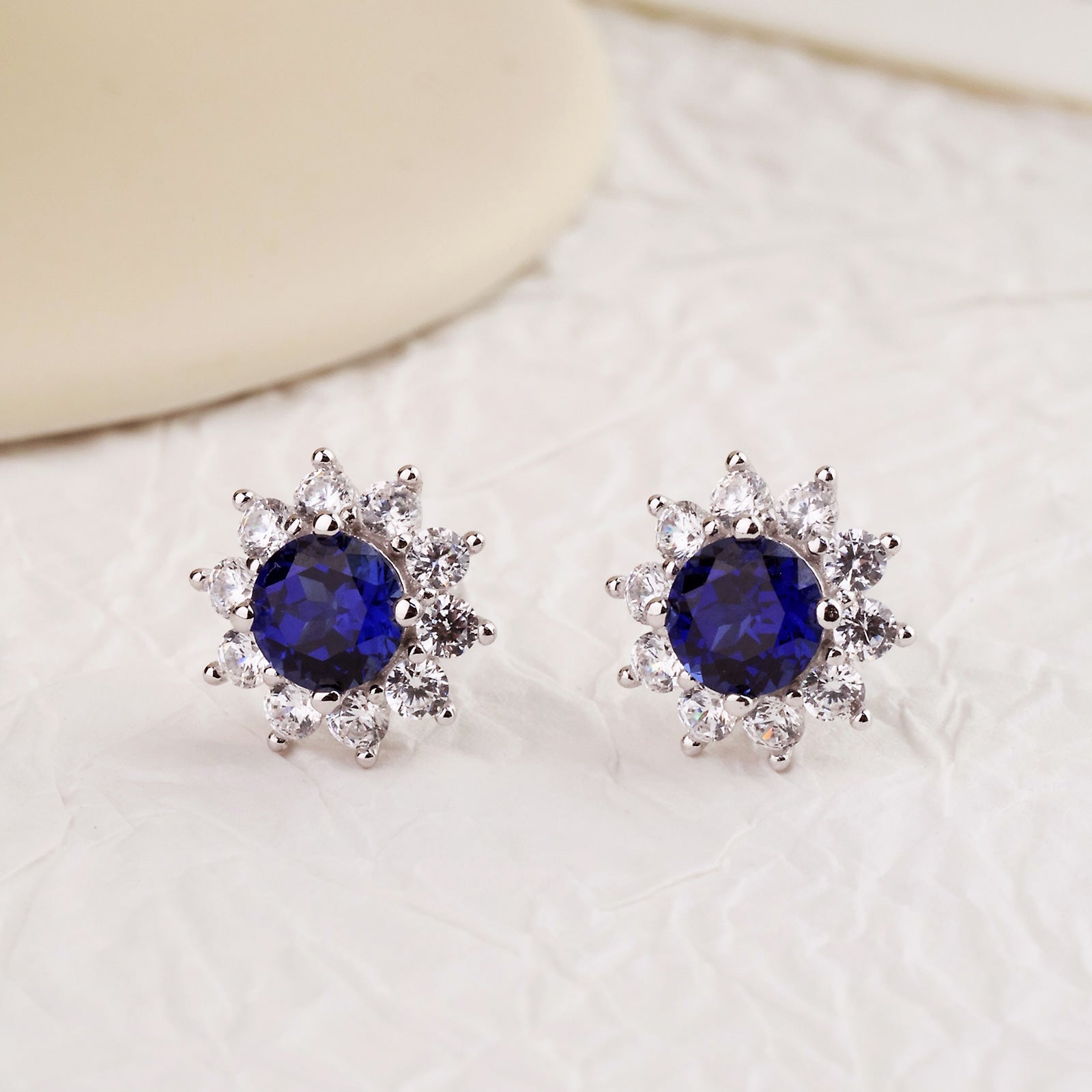 Close-up of blue lab-created sapphire and cubic zirconia halo stud earrings