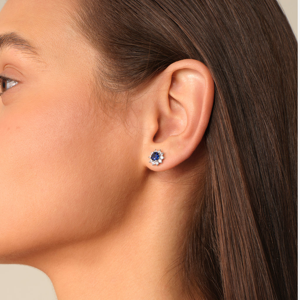 Side view of a model wearing a sapphire halo stud earring close to the earlobe