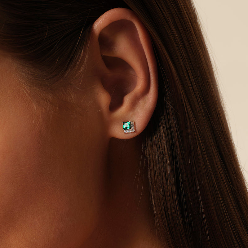 Model wearing a square lab-grown emerald stud earring close to the earlobe