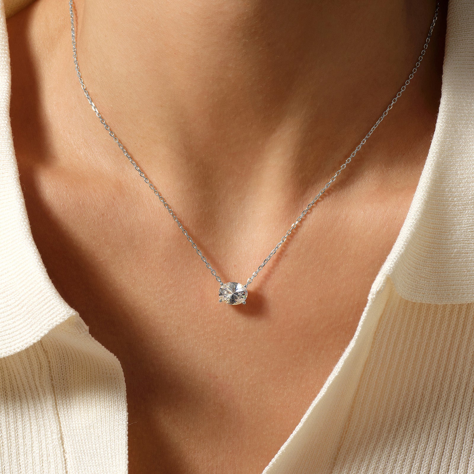 Model wearing oval cubic zirconia pendant necklace in white gold color