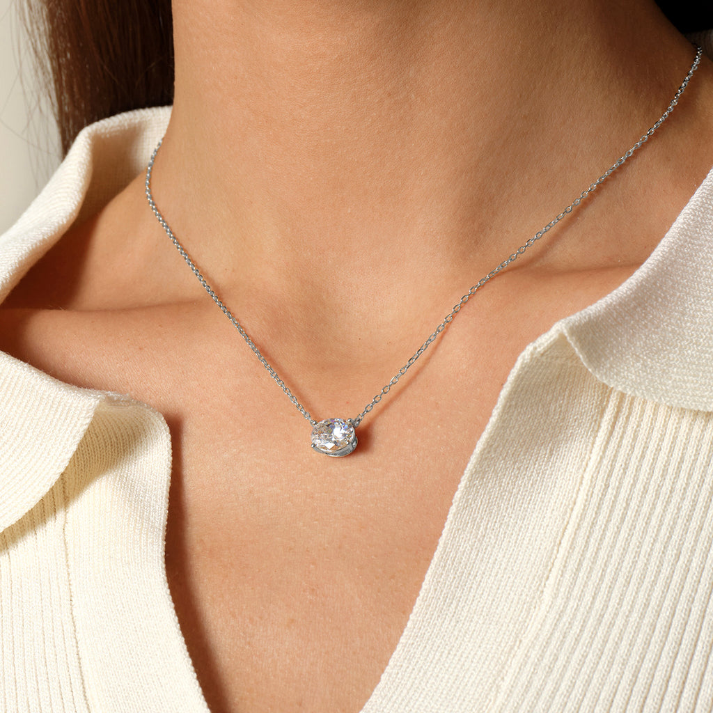 Model wearing oval cubic zirconia pendant necklace in white gold color, close view