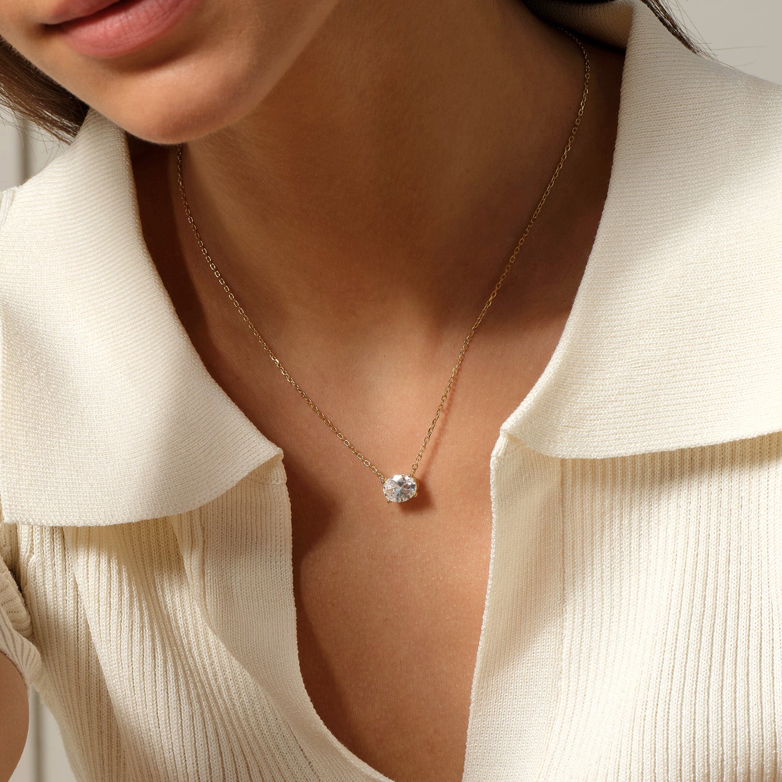Model wearing oval cubic zirconia pendant necklace in yellow gold color, close view