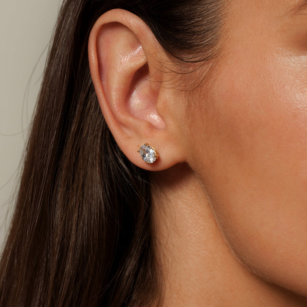 Model wearing oval cubic zirconia stud earrings in gold color