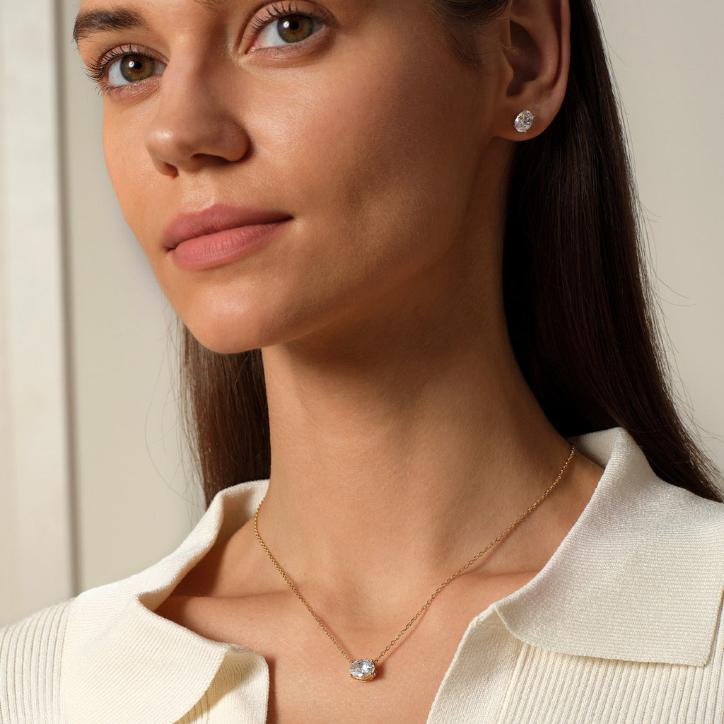 Model wearing oval cubic zirconia stud earrings in gold color with neutral outfit