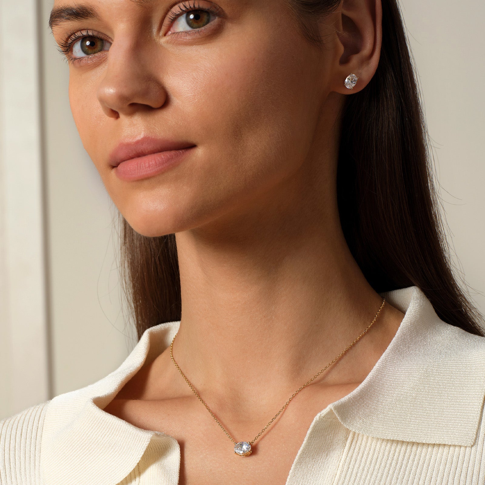 Model wearing oval cubic zirconia stud earrings in gold color with neutral outfit