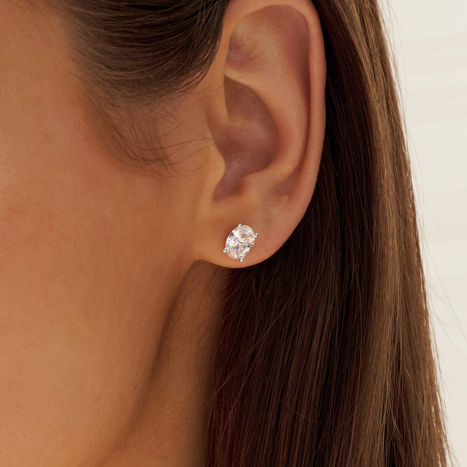 Close-up of model wearing oval cubic zirconia stud earrings in silver color