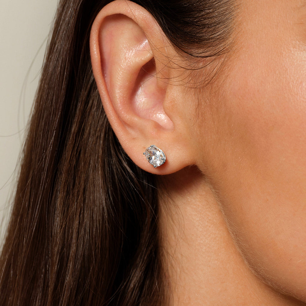 Model wearing oval cubic zirconia stud earrings in silver color