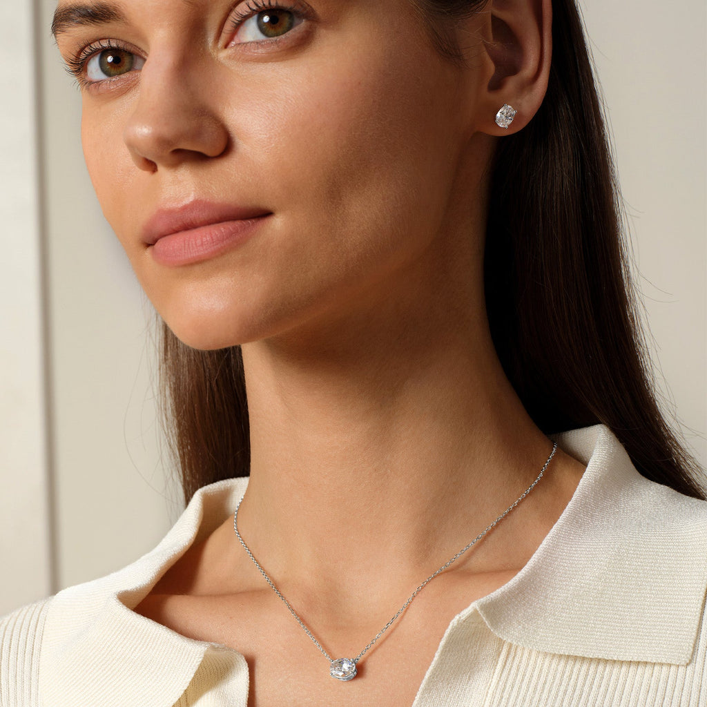 Model wearing oval cubic zirconia stud earrings in silver color with neutral outfit