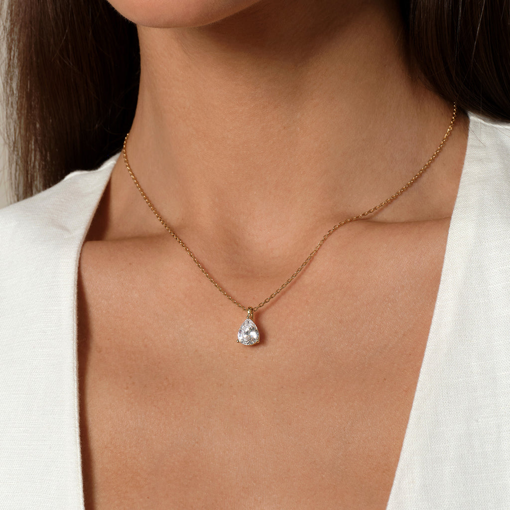 Model wearing pear-shaped cubic zirconia pendant necklace in yellow gold color