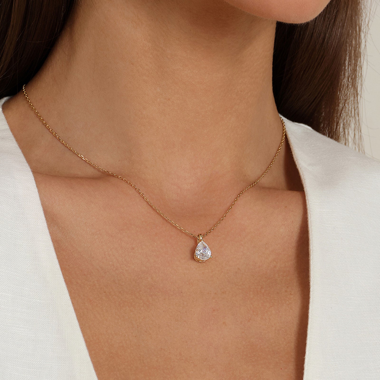 Model wearing pear-shaped cubic zirconia pendant necklace in yellow gold color, close view