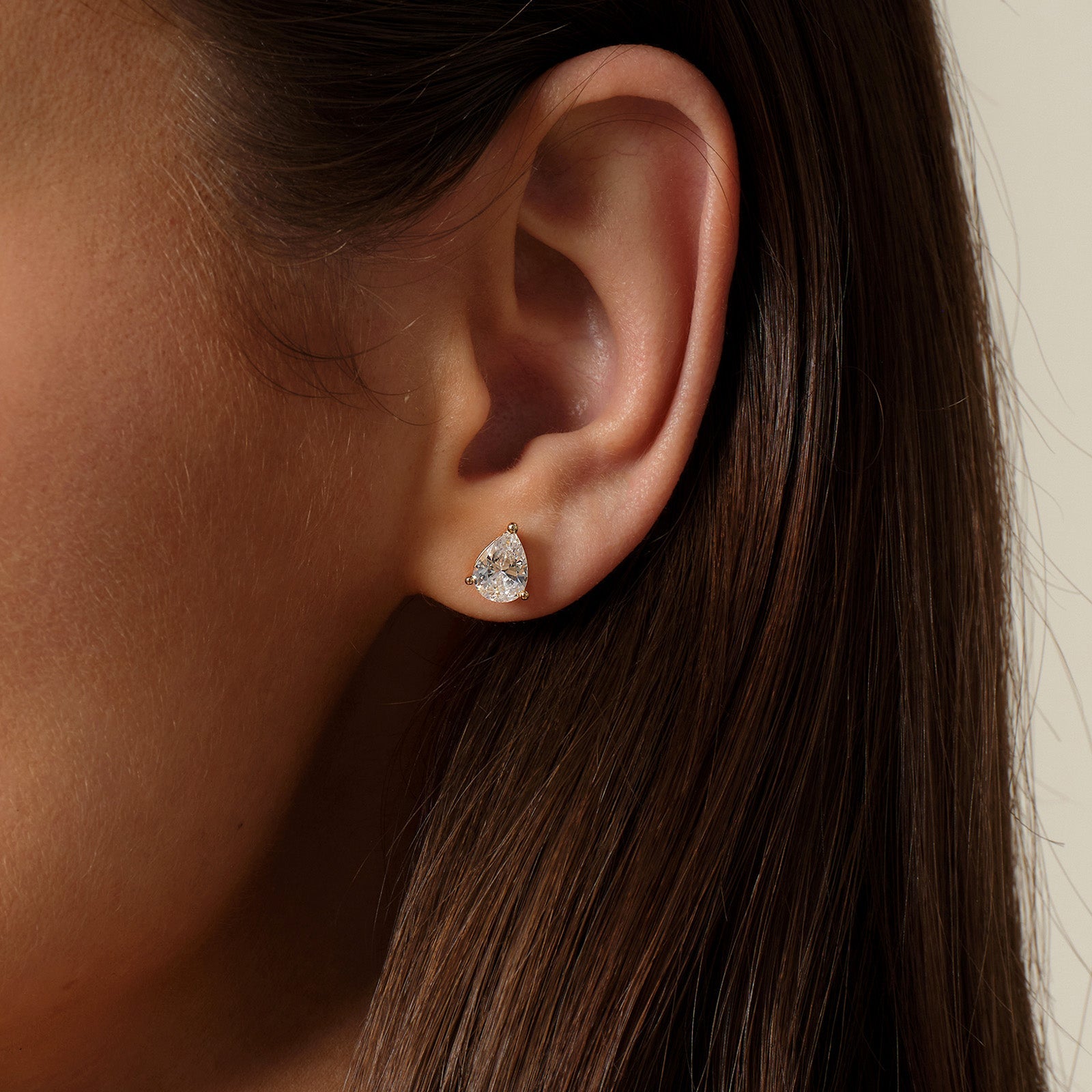 Model wearing pear-shaped cubic zirconia stud earrings in gold color angle view
