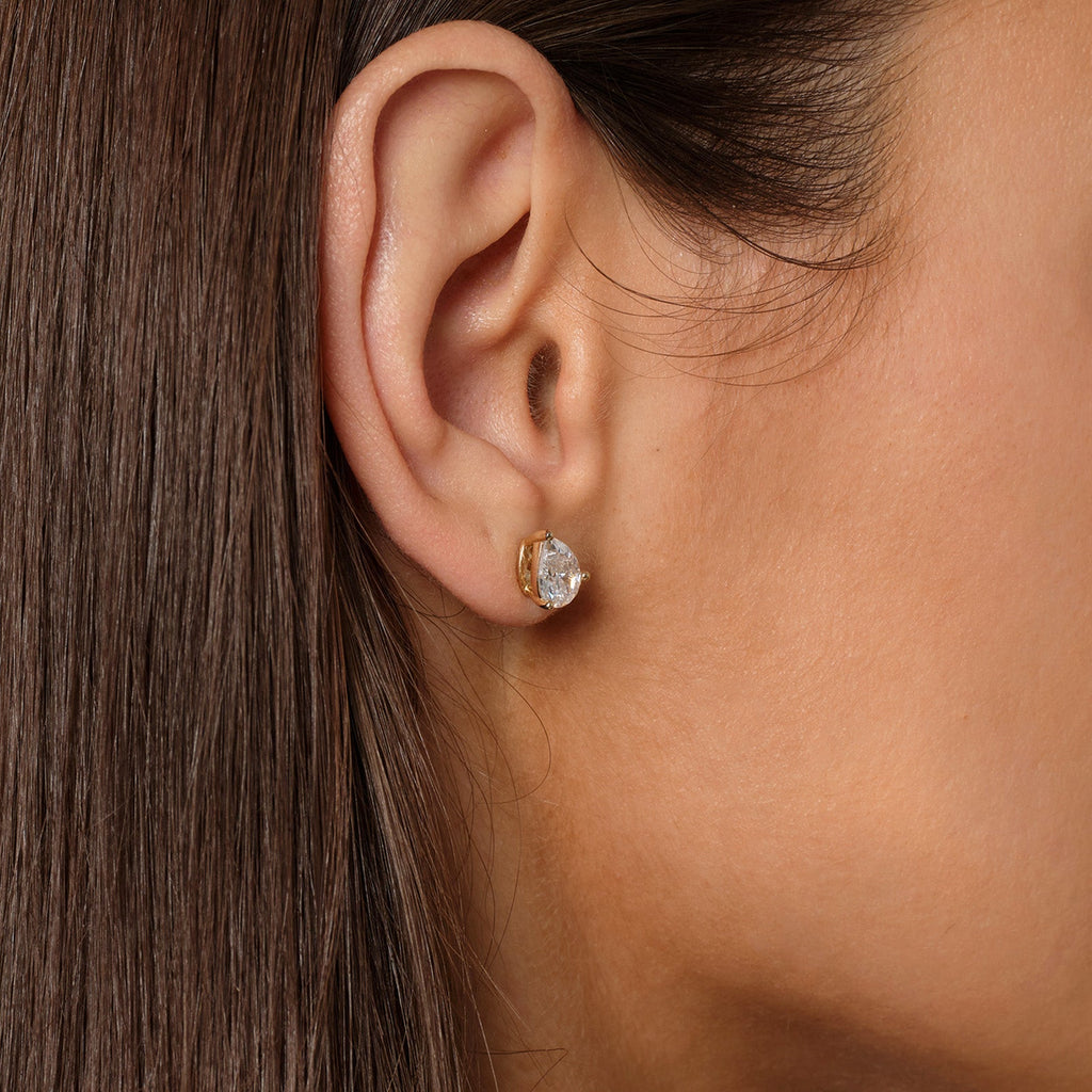 Close-up of model wearing pear-shaped cubic zirconia stud earrings in gold color