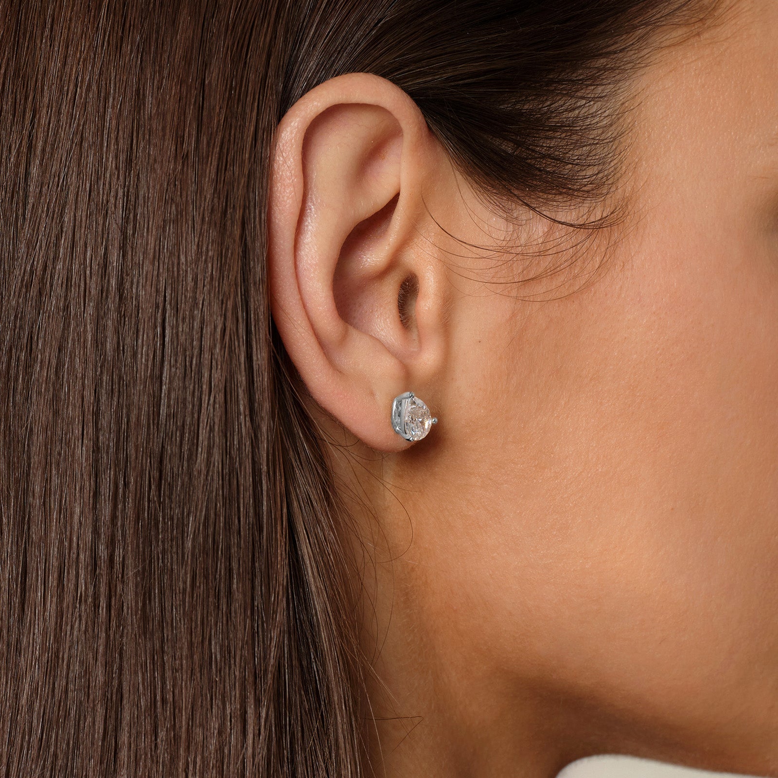 Close-up of model wearing pear-shaped cubic zirconia stud earrings in silver color