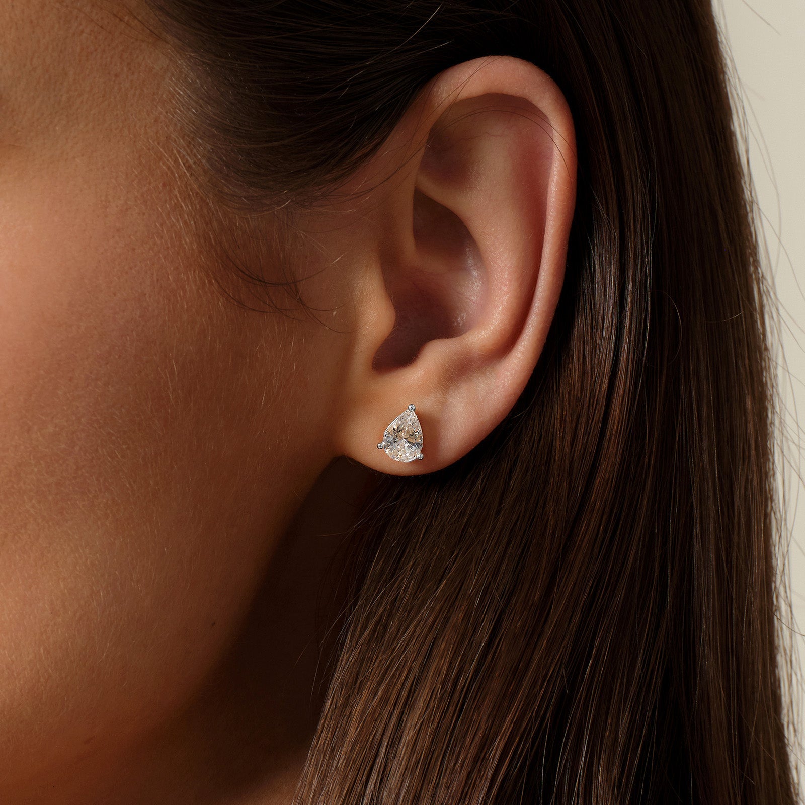 Model wearing pear-shaped cubic zirconia stud earrings in silver color